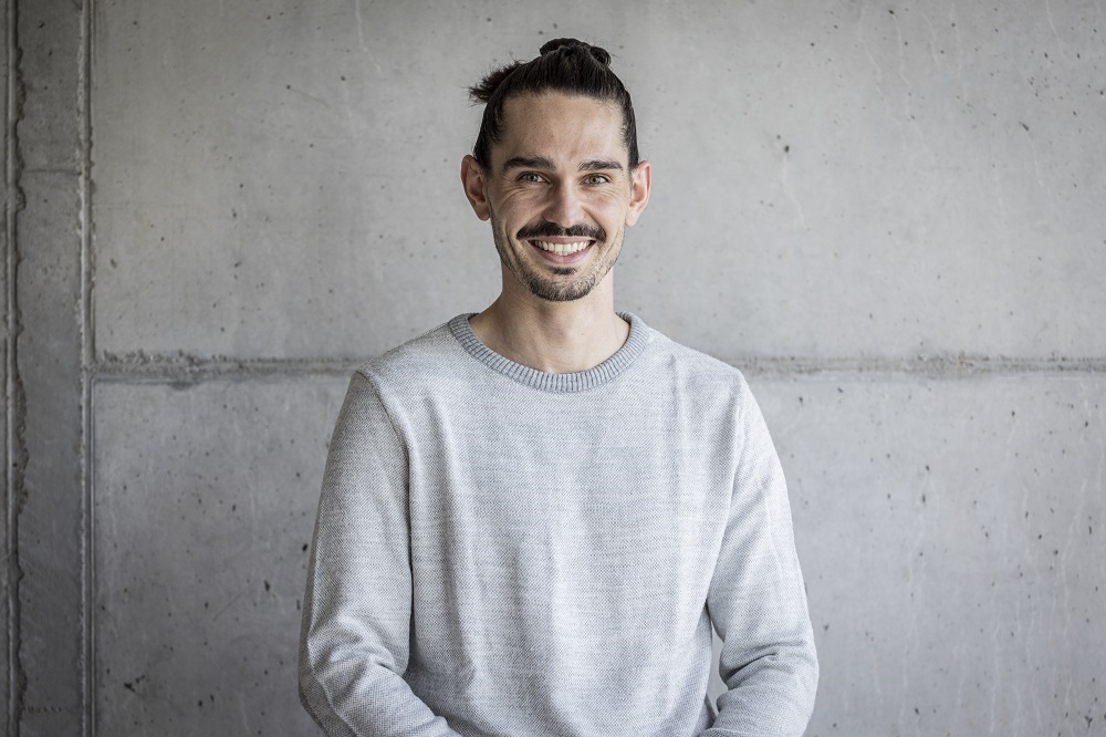 Ein Foto von dem Mann Michael Deuber, Campusbetrieb und Empfang, vor einer grauen Wand.